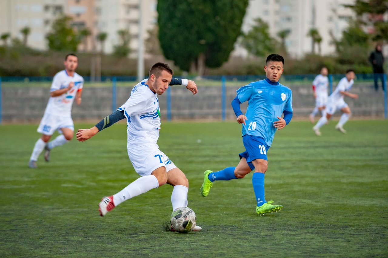 Football players in motion during a competitive soccer match on an outdoor field.