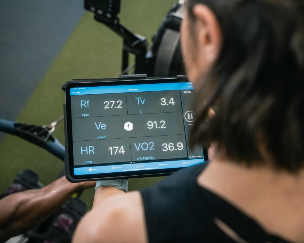 Adult man reviewing fitness metrics on a tablet during a workout session at the gym.
